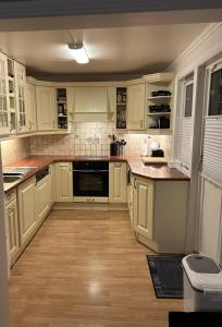 a kitchen with white cabinets and a wooden floor at Nydelige Tromsdalen - rom i enebolig in Tromsø