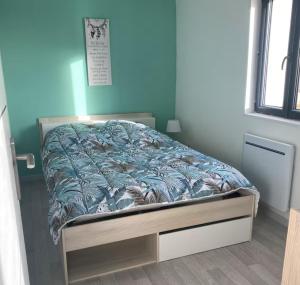 a bed in a bedroom with a blue wall at Maison du Champblanc 2 chambres in Bourbon-Lancy