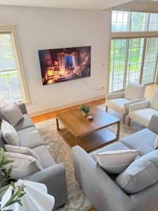 a living room with couches and a tv on the wall at Cozy Ithaca Retreat - Fenced Yard - 7 min to Cornell in Ithaca