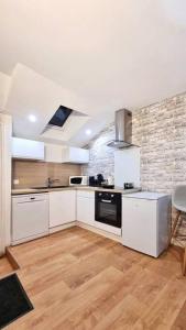 una cucina con mobili bianchi e un muro di mattoni di Appartement T2 proche gare et centre ville a Châteauroux