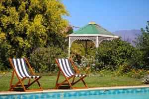 two chairs and a gazebo next to a pool at Luxury Poolside Villa Irene in Cape Town