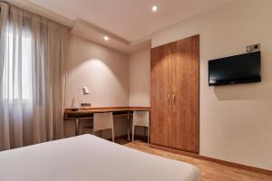 a hotel room with a bed and a desk at Hotel Avenida in Zaragoza