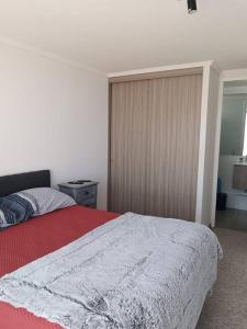 a bedroom with a bed with a red and white blanket at Departamento familiar Iquique in Iquique