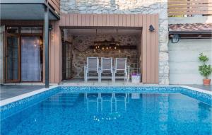 une piscine avec deux chaises à côté d'une maison dans l'établissement Beautiful Home In Tribalj, à Tribalj