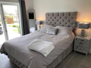 a bedroom with a large bed with a large headboard at Brand new purpose built 3 bedroom holiday barn in Bonvilston