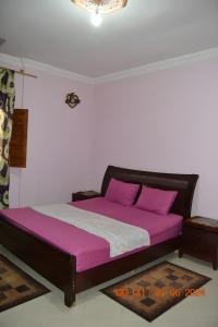 a bed with purple sheets in a room at Appartement lumineux et spacieux en plein centre ville in Ouarzazate