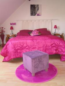 a bedroom with a pink bed with a purple comforter at La Bonardière in Gevry