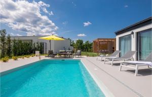 a swimming pool with chairs and an umbrella next to a house at Villa Lu in Šibenik