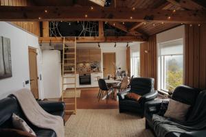 a living room with couches and a table and a kitchen at Ourtal Cottage in Burg-Reuland