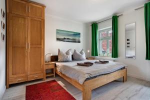 1 dormitorio con 1 cama con cortinas verdes en Bäckerhus - Ferienwohnung 3, en Wiek auf Rügen