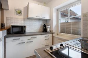 Una cocina con gabinetes blancos y un fregadero y una ventana. en Bäckerhus - Ferienwohnung 3, en Wiek auf Rügen