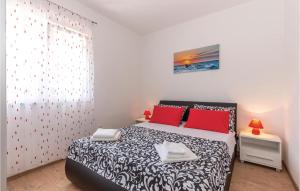 a bedroom with a black and white bed with red pillows at Amazing Home In Kostrena in Kostrena