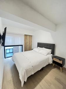 Un dormitorio blanco con una cama grande y una ventana. en Departamento de Estreno en Miraflores, en Lima
