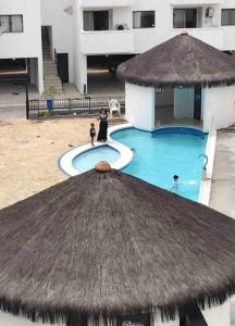 a view of a swimming pool with a straw hut at Linda cobertura duplex frente pro mar. in Arraial do Cabo