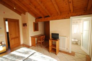 a bedroom with a bed and a desk with a television at Garni Viggiona in Trarego