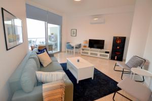 a living room with a blue couch and a table at Awesome Sea & Marina View City Center 1 Bdr Flat in Larnaka