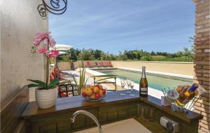 a table with a bottle of wine and fruit next to a swimming pool at Lovely Home In Vallabregues in Vallabrègues