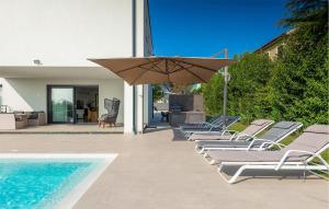a row of lounge chairs with an umbrella next to a swimming pool at Villa Auri in Pula