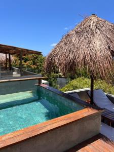 a swimming pool with a thatch roof and a resort at Casa Flor São Miguel dos milagres 11 in Barra do Camaragibe