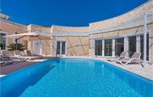 a swimming pool with chairs and an umbrella at Feriatum Lissa in Zadar