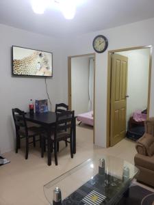 a living room with a table and chairs and a clock at Oceanview 2-bedroom Condo Unit in Dumaguete