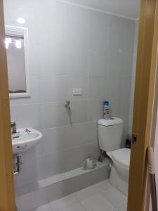 a white bathroom with a toilet and a sink at Oceanview 2-bedroom Condo Unit in Dumaguete