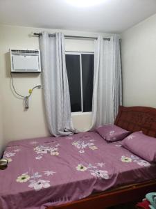a bedroom with a bed with purple sheets and a window at Oceanview 2-bedroom Condo Unit in Dumaguete