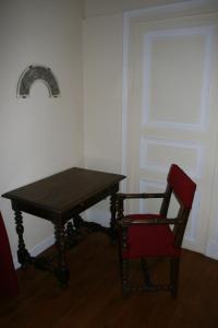 une table en bois et une chaise rouge à côté d'une fenêtre dans l'établissement Château Hôtel de Warenghien, à Douai