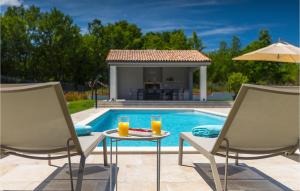 a pool with two chairs and a table with orange juice at Villa Tre Olive in Pula