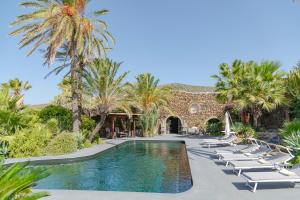 a resort swimming pool with lounge chairs and palm trees at Don Mario Resort adults only in Pantelleria