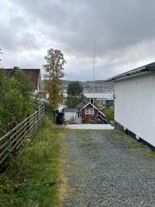 una strada sterrata accanto a un edificio bianco e a una recinzione di Romslig hybel leilighet a Tromsø