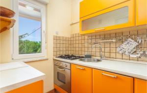 kuchnia z pomarańczowymi szafkami, umywalką i oknem w obiekcie Nice Home In Risika With House Sea View w mieście Risika
