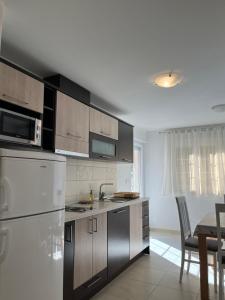 een keuken met een witte koelkast en een tafel bij Apartments KARLO in Baška Voda