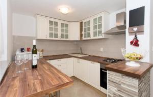 a kitchen with white cabinets and a counter with wine glasses at Amazing Home In Bajagic in Bajagić