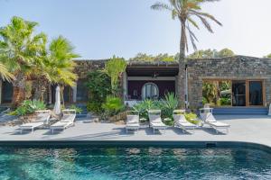 a swimming pool with chairs and a house at Don Mario Resort adults only in Pantelleria