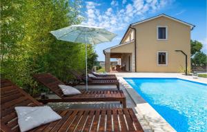 a pool with chairs and an umbrella next to a house at Villa Nino in Rovinj