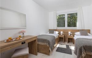 a room with two beds and a table and two windows at Nice Home In Kraljevica With Wifi in Kraljevica