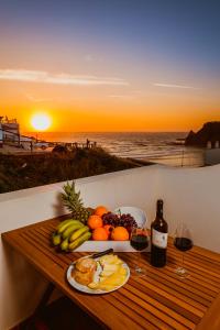 una mesa con una bandeja de fruta y copas de vino en Casas do Zé, en Odeceixe