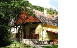 ein gelbes Haus mit einer Veranda und Bäumen in der Unterkunft Fűrészmalom vendégház in Matrakeresztes