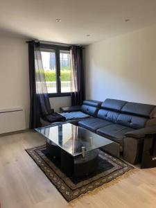 un soggiorno con un divano e un tavolo di vetro di Charmant appartement Entre lacs et montagnes ! a Culoz