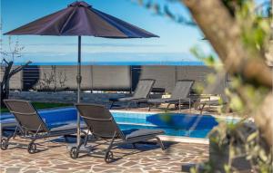 Un grupo de sillas y una sombrilla junto a una piscina. en Villa Druskovic, en Umag