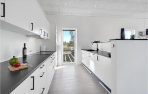 a kitchen with white cabinets and a bottle of wine at 3 Bedroom Amazing Home In Rødby in Rødby