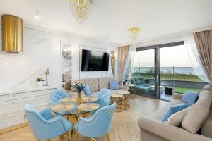 a living room with a table and blue chairs at Apartament Holiday Gold in Rewal