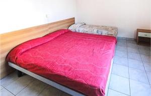 a bed with a red comforter in a room at Lovely Apartment In Rosolina Mare in Rosolina Mare