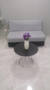 a vase with purple flowers on a table in front of a couch at Centrico y comodo monoambiente in Santa Cruz de la Sierra