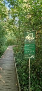 a sign next to a wooden boardwalk in a forest at Agréable chambre in Prévessin-Moëns +10 photos