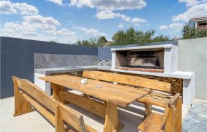 a wooden table and benches on a patio with a fireplace at Cozy Home In Rab With Wifi in Rab