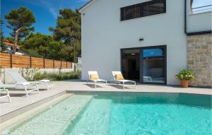 a swimming pool with two chairs and a house at Villa Stella Mare in Premantura