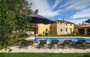 a group of chairs and an umbrella next to a pool at Villa Ive in Orbanići