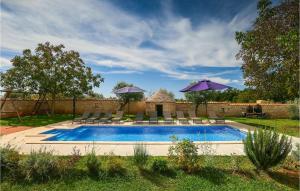 a pool with chairs and umbrellas in a yard at Villa Ive in Orbanići